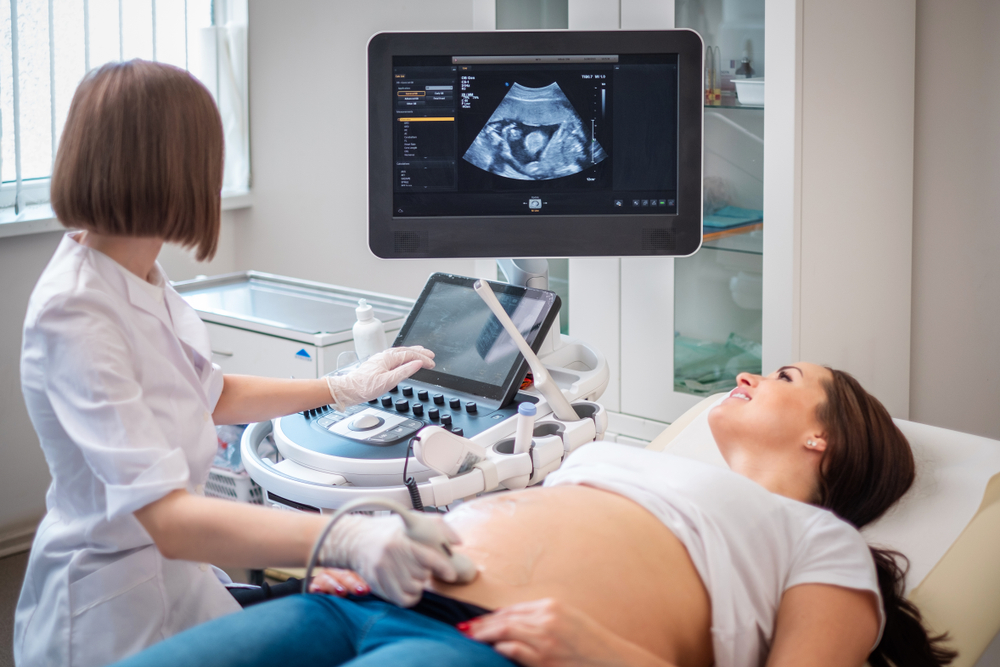 Healthcare professional performing prenatal ultrasound scan with medical imaging equipment