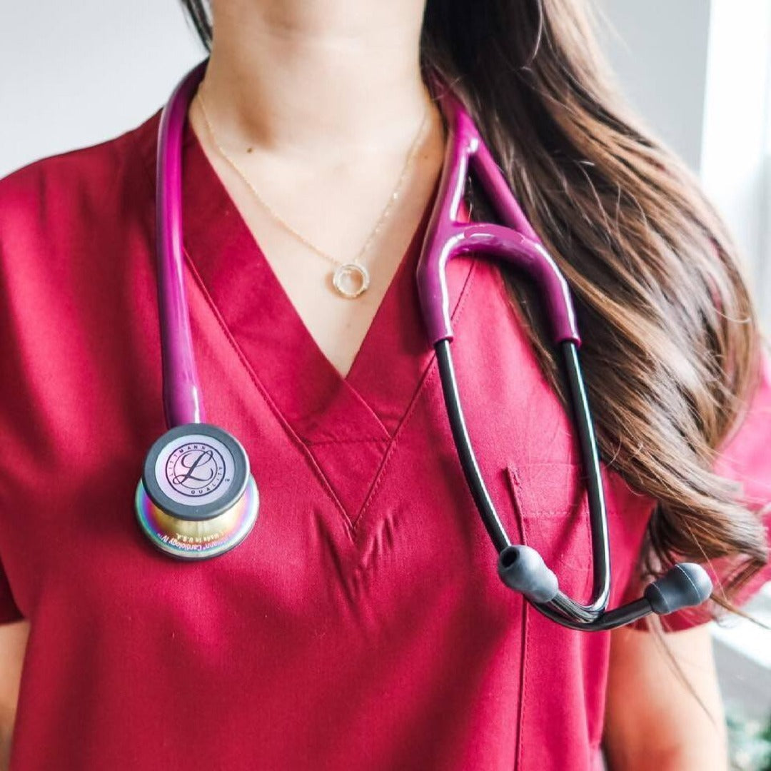 Medical professional in maroon scrubs with pink stethoscope, healthcare uniform