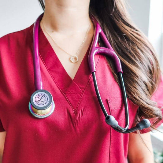 Medical professional in maroon scrubs with pink stethoscope, healthcare uniform
