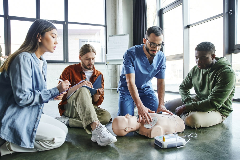 CPR training session with instructor demonstrating on medical manikin and trainees observing