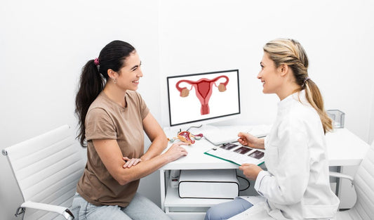 Female doctor consulting patient in gynecology clinic with uterus anatomy on monitor