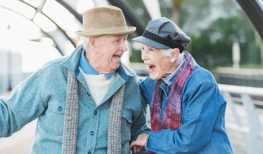 Happy elderly couple laughing outdoors in winter clothing, senior wellness lifestyle