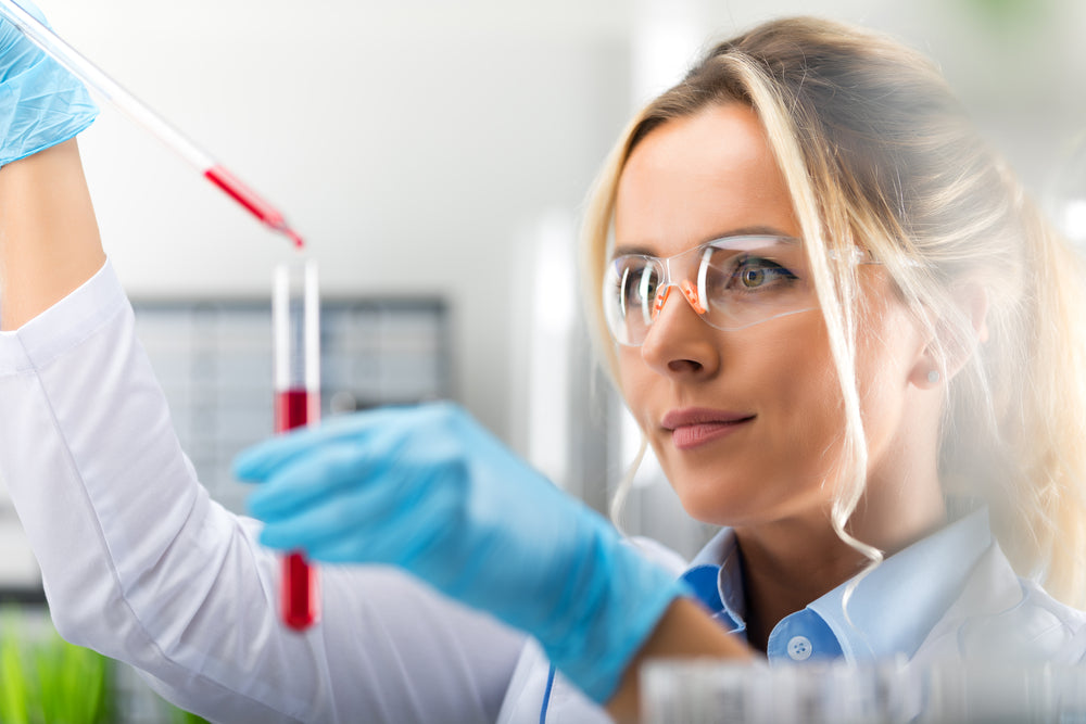 Scientist in lab coat using pipette with blood sample in laboratory setting