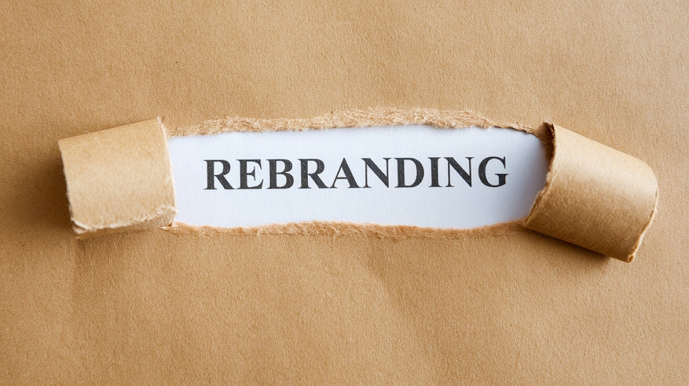 Brown paper torn to reveal the word rebranding on white background, business concept