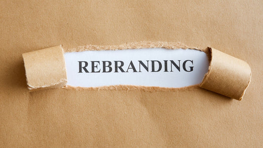 Brown paper torn to reveal the word rebranding on white background, business concept