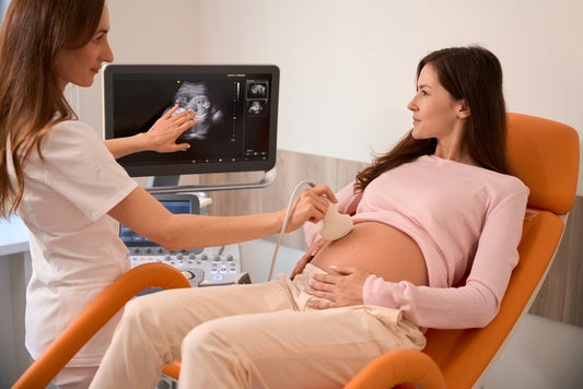 Pregnant woman getting abdominal ultrasound scan by doctor in modern clinic