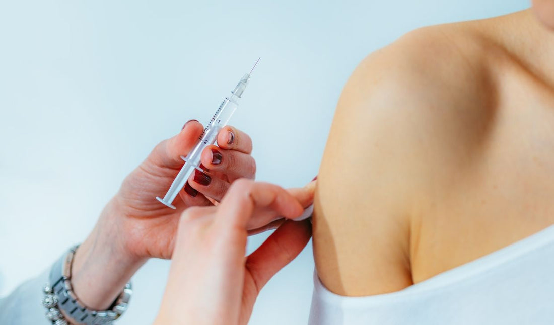 Nurse administering syringe injection into patient's upper arm, medical supplies concept