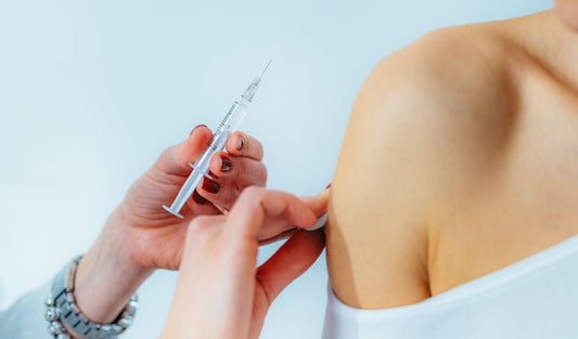 Nurse administering syringe injection into patient's upper arm, medical supplies concept