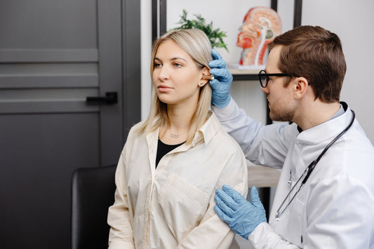 Doctor examining woman's ear with otoscope in medical office, healthcare checkup