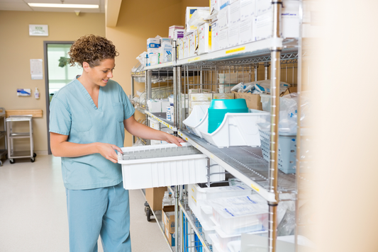 Healthcare worker in scrubs organizing medical supplies on a shelf in a clinical setting