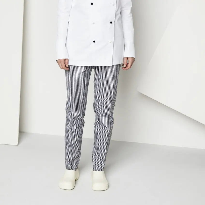 Person wearing a white double-breasted uniform jacket, checkered trousers, and white work shoes standing indoors