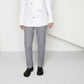 Person wearing white chef jacket, checkered chef trousers, and black slip-resistant shoes