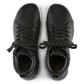 Top view of black lace-up medical shoes with padded collar and white soles on white background.