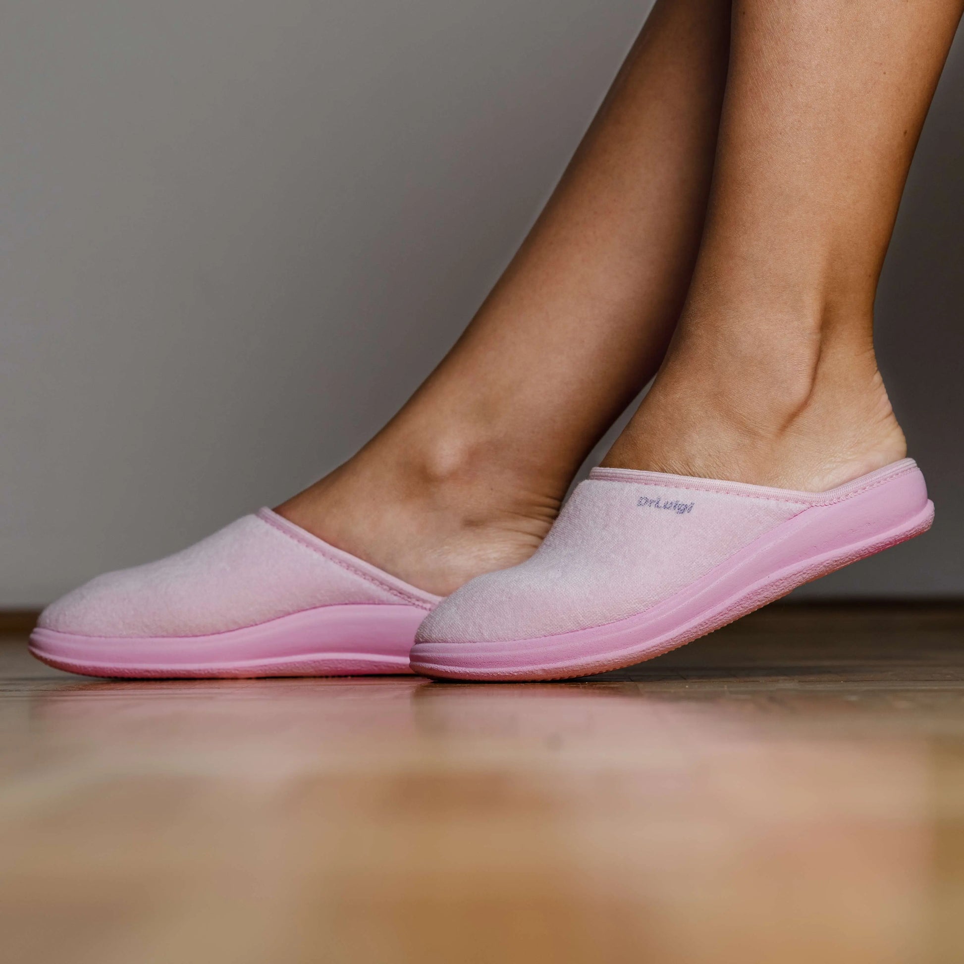 Pink orthopedic slippers on wooden floor, comfortable indoor footwear for women