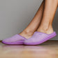Person wearing light purple indoor medical slippers on wooden floor