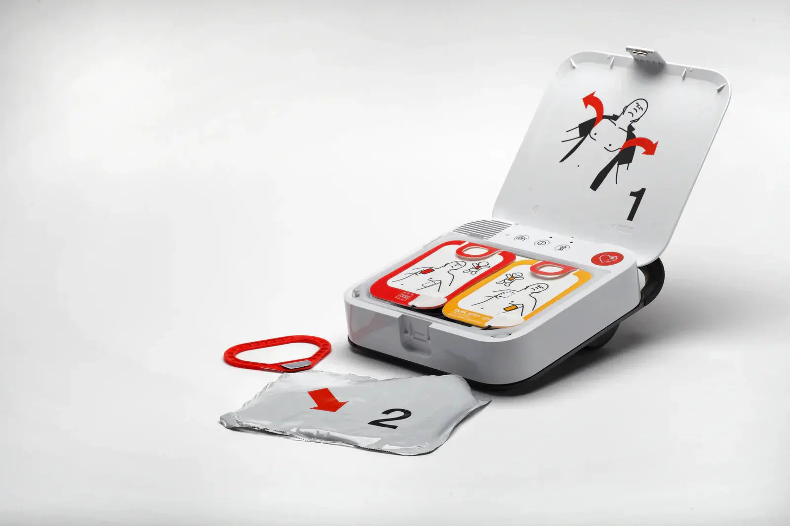 Automated external defibrillator with open lid and electrode pads on white background