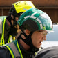 Emergency personnel wearing protective helmets and hi-vis vests in an outdoor medical response