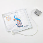 Zoll Cardiac Science Powerheart G5 pediatric defibrillator pads attached to a child's chest for emergency cardiac treatment.
